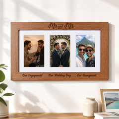 A wooden picture frame with three photographs of two men, one in a wedding dress and the other in a casual outfit, along with the text "Our Engagement, Our Wedding Day, Our Honeymoon" written on the frame.
