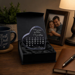 a heart-shaped calendar with a personal message, placed on a desk next to a mug and a pen.