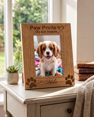 A wooden picture frame with a photo of a small dog inside, placed on a table near a window.