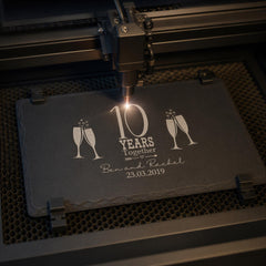 A black slate with a laser engraving of a champagne glass and the text "10 YEARS TOGETHER" and "Ben and Rachel 23.03.2019" on it.