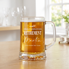 A glass mug filled with beer, placed on a wooden table, with a personalized message printed on it.