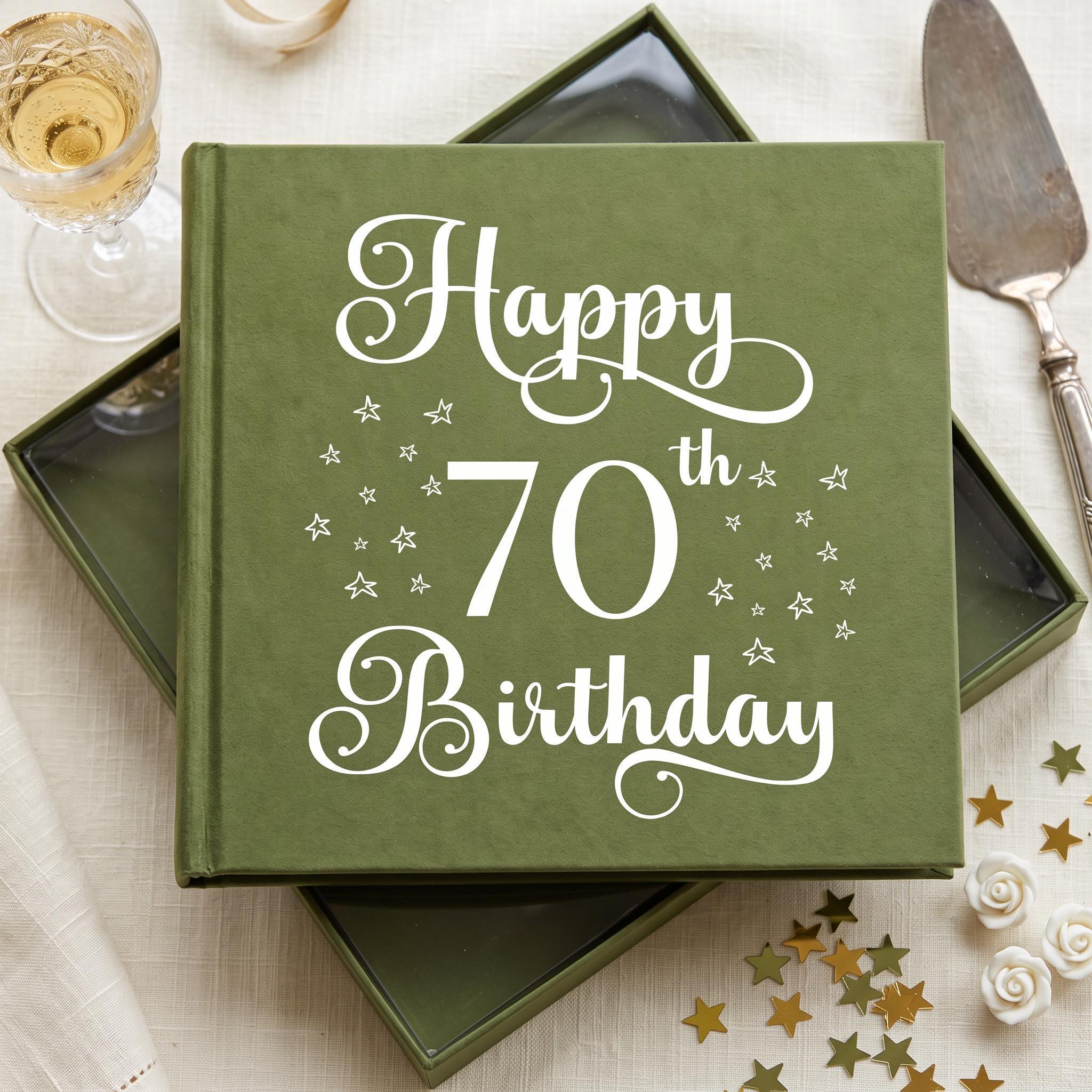 a green book with the text "Happy 70th Birthday" printed on it, along with white stars. The book is placed on a table with a wine glass, a cake, and some gold stars scattered around it.