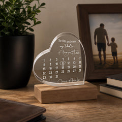 a heart-shaped photo frame with a calendar inside, placed on a wooden stand. The frame has a photo of a man and a child inside, and the calendar displays the day you became my dad on August 8, 2020.