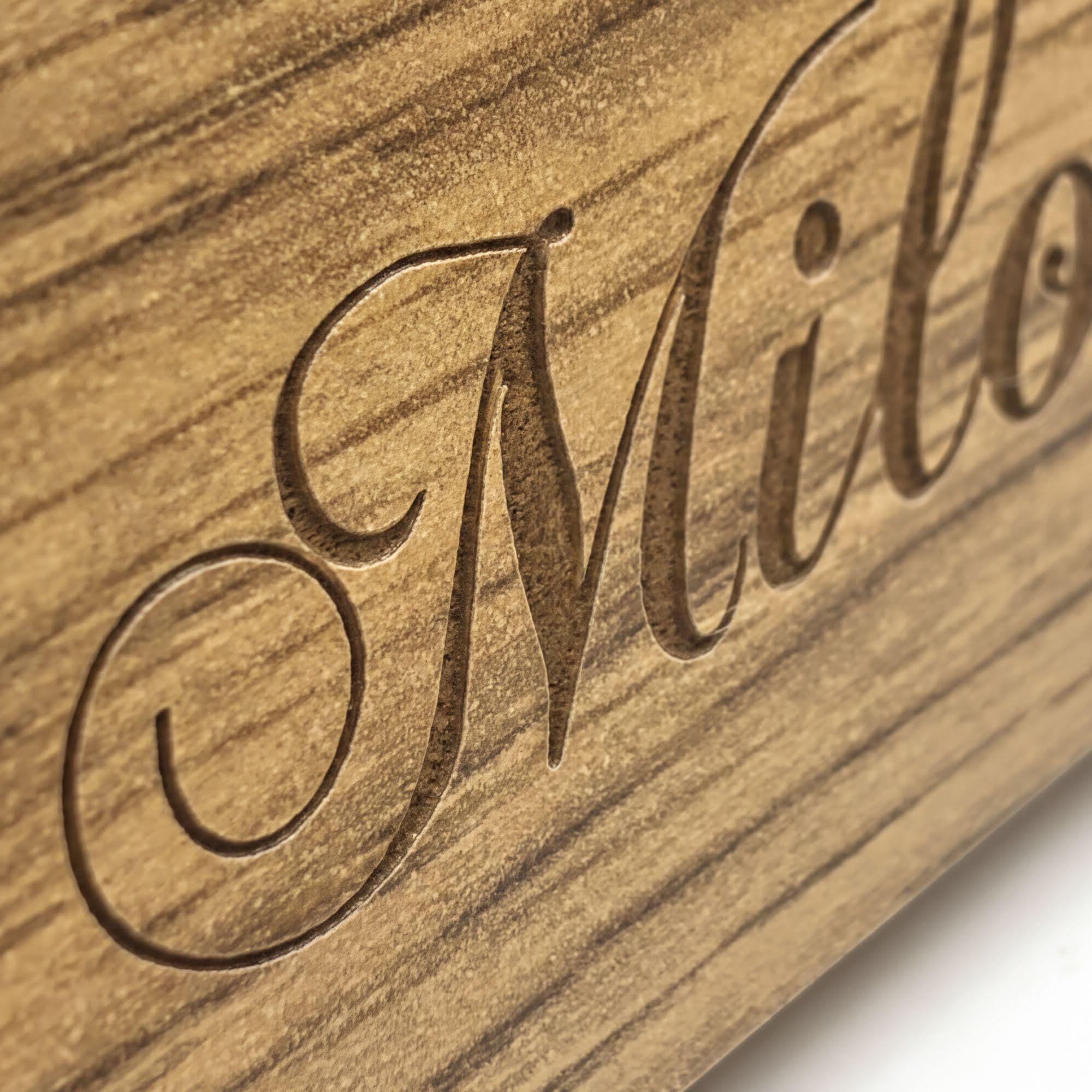 a close-up view of a wooden surface with a carved inscription or text in a cursive font.