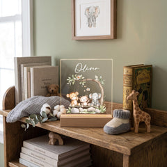 A wooden bookshelf displaying various items, including a framed picture of an elephant, a wooden toy giraffe, a wooden toy elephant, and a wooden toy giraffe. There are also several books and a wooden toy elephant on the shelf.