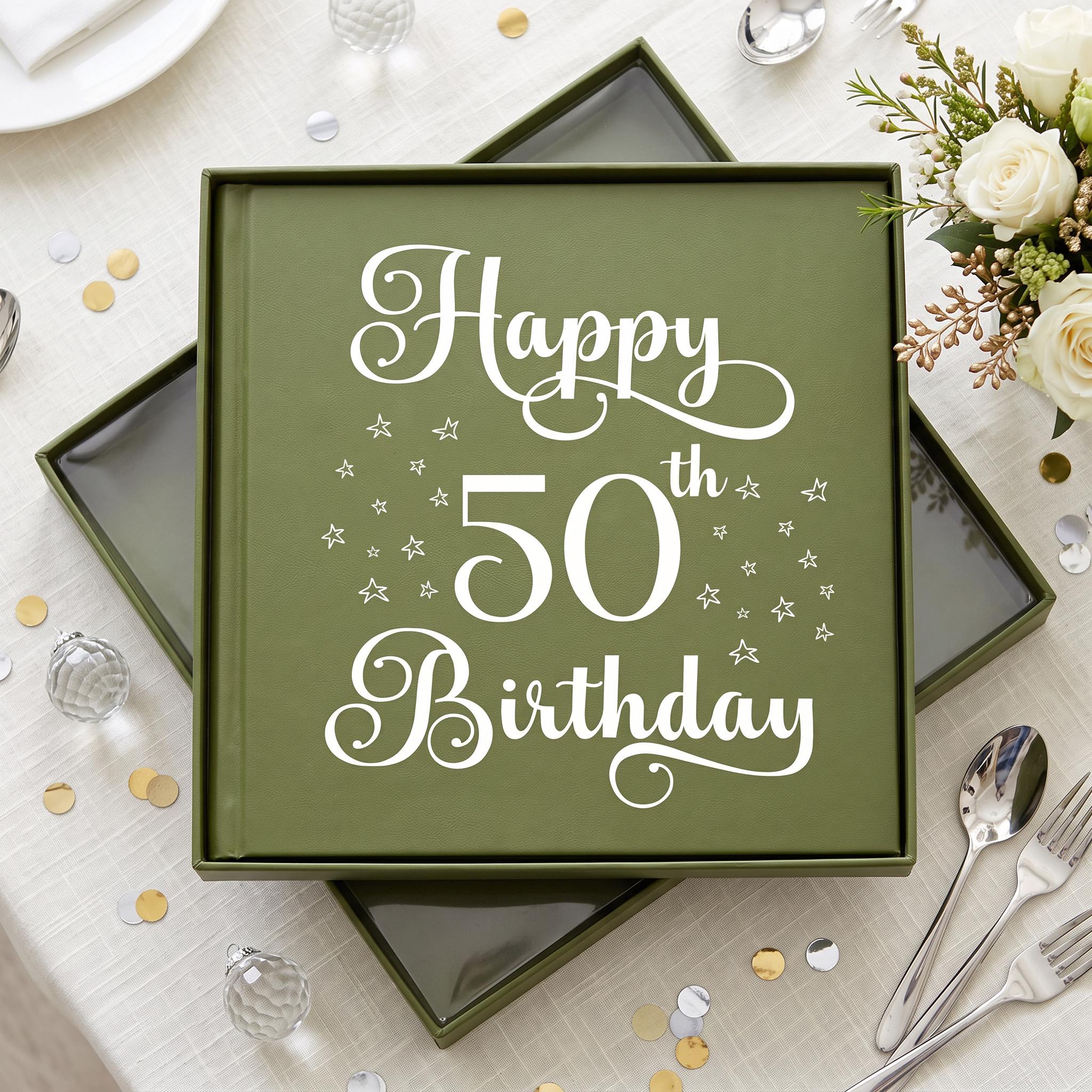A green box with a white and gold design, displaying the text "Happy 50th Birthday" surrounded by stars. The box is placed on a table with a white tablecloth, and there are silverware and a bouquet of flowers nearby.