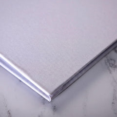 A close-up view of a white, textured surface, possibly a marble or stone, with a folded or closed object placed on top of it.