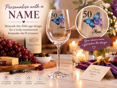 a wine glass with a personalized name on it, along with a 50th birthday gift and a table setting with a bottle of wine, grapes, and cheese.