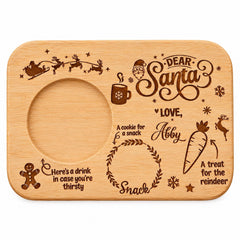 The image is a wooden tray with various Christmas-themed illustrations and text. It includes a Santa Claus sleigh, a cookie, a carrot, a treat for the reindeer, and a cookie for a snack. The text on the tray includes phrases like "Dear Santa", "Love", "Here's a drink in case you're thirsty", and "A treat for the reindeer". The overall layout and design of the tray suggest it is a personalized or handmade item, possibly for a Christmas-themed gift or decoration.
