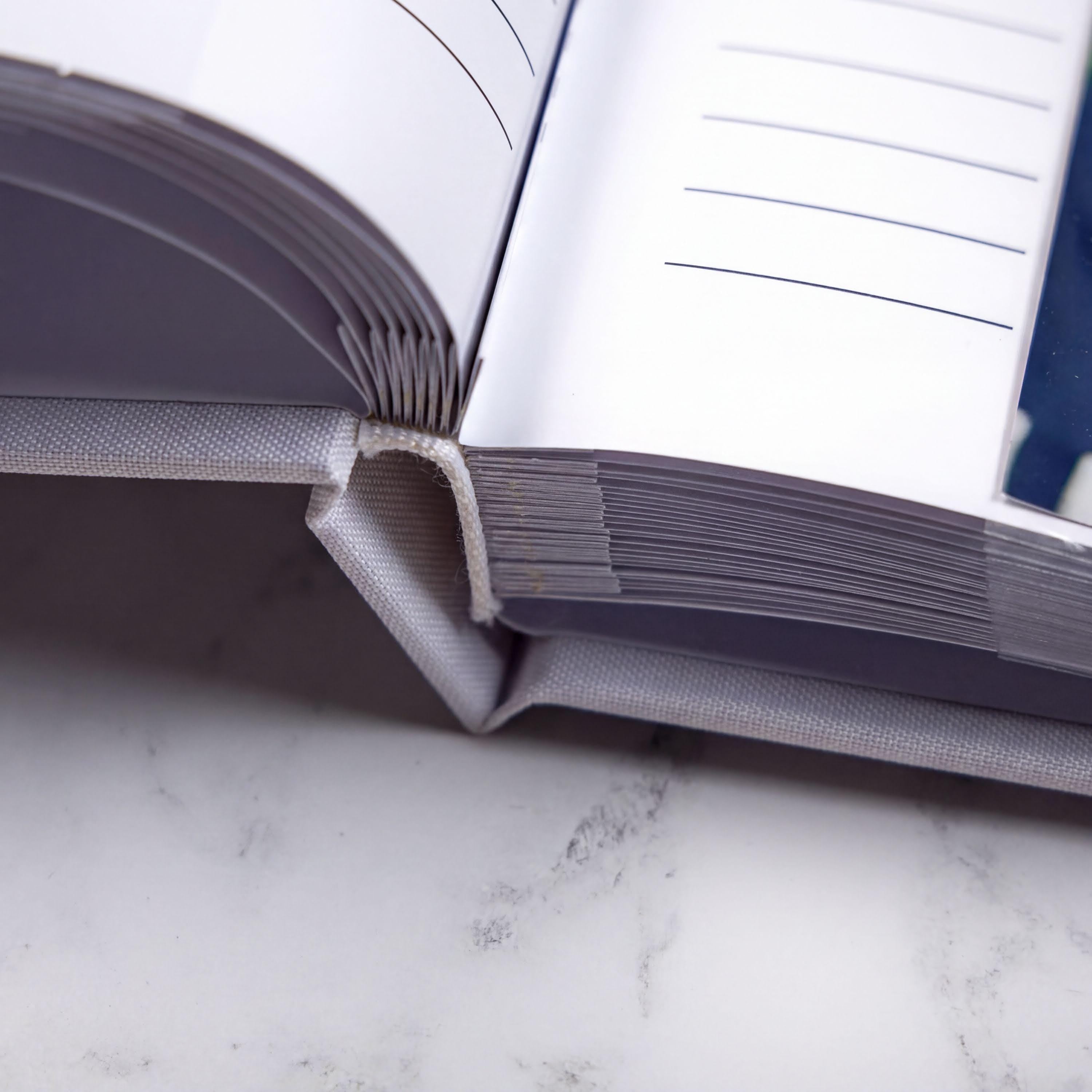 an open book with blank pages, resting on a white marble surface.