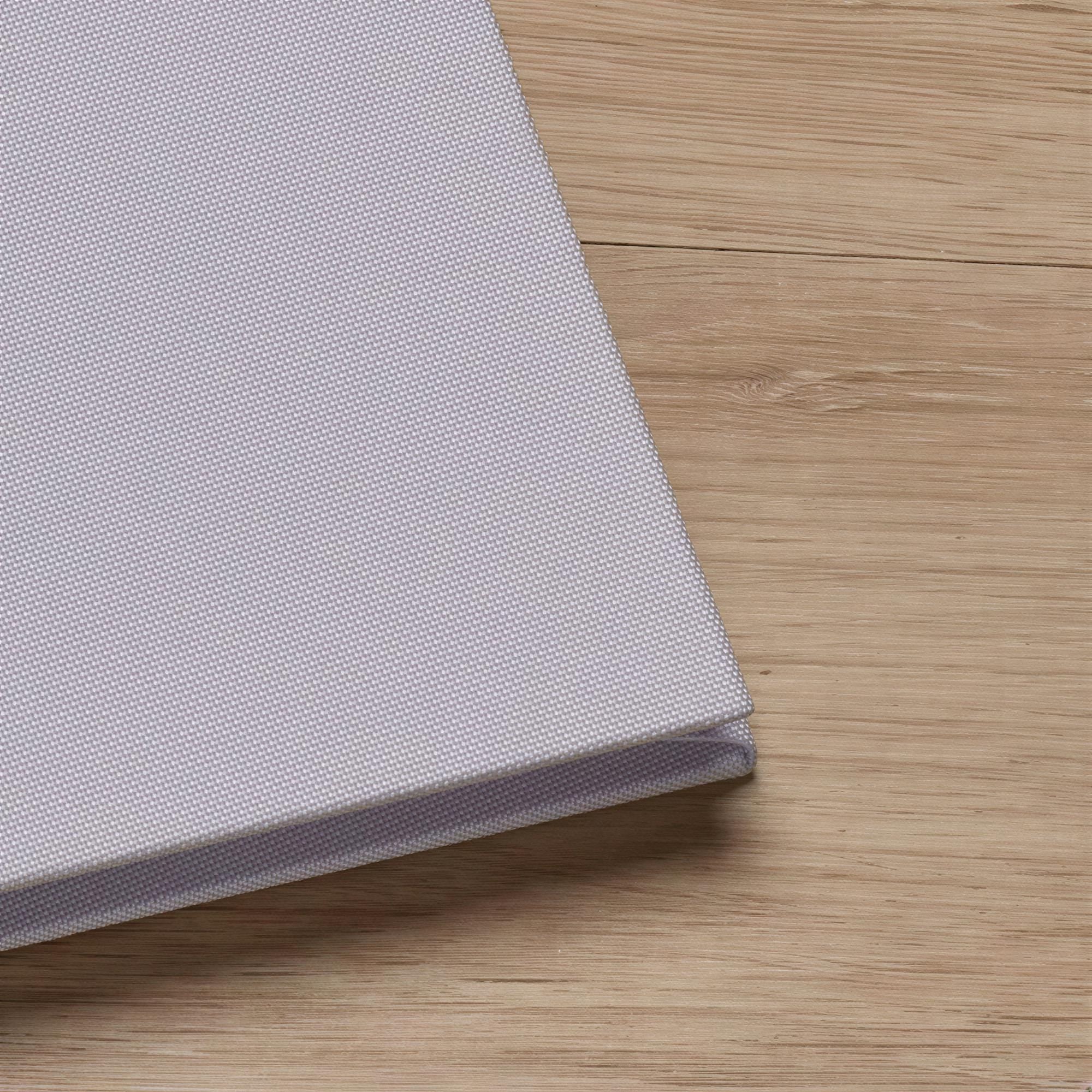 A close-up view of a light-colored fabric or material, possibly a piece of clothing or a textile, resting on a wooden surface.