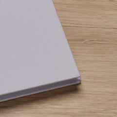 A close-up view of a light-colored fabric or material, possibly a piece of clothing or a textile, resting on a wooden surface.