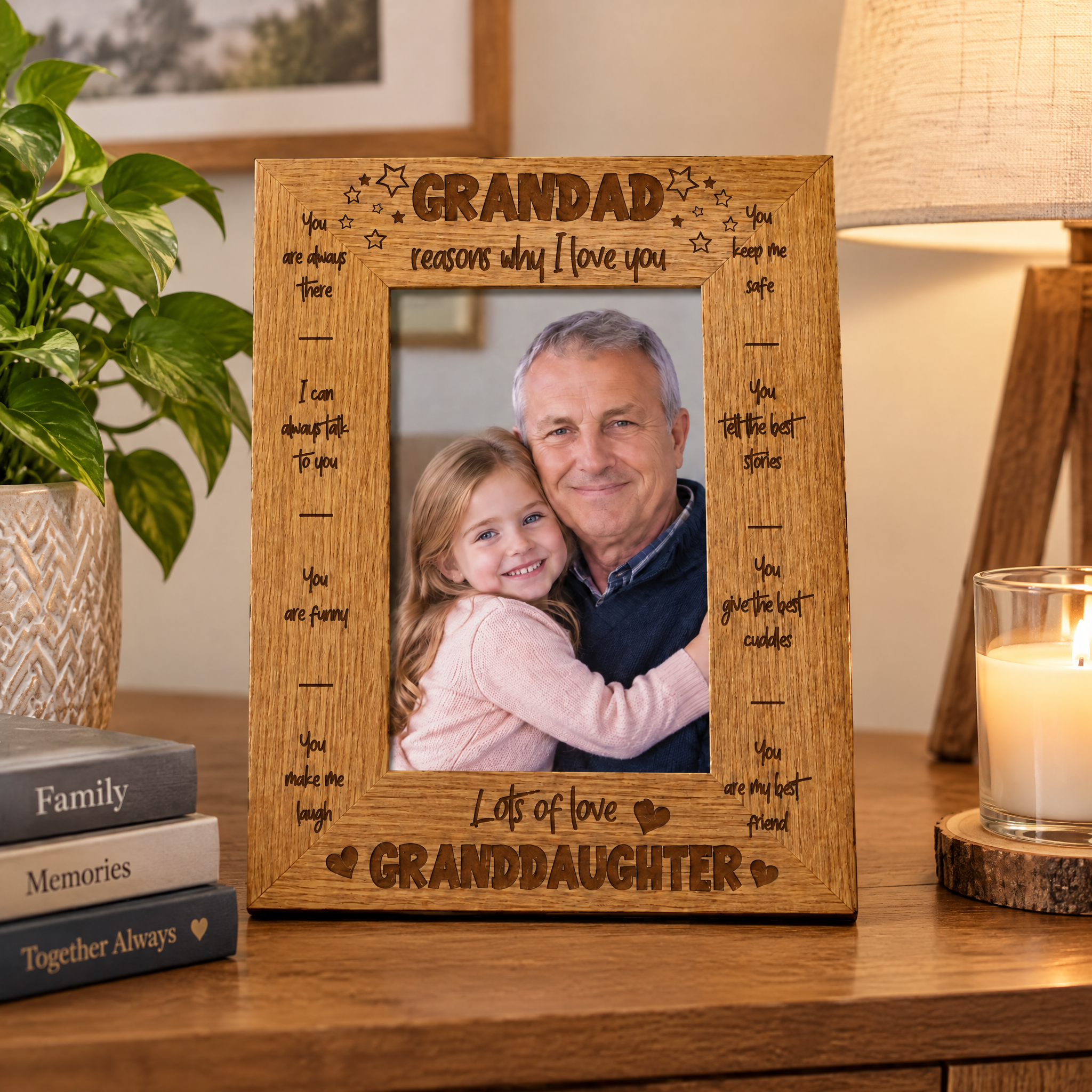 A wooden picture frame with a photo of a man and a young girl, surrounded by various books and a candle on a wooden surface.