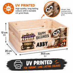 The image is a wooden crate with a Halloween-themed design printed on it. The crate is described as UV printed, which means it has a high-quality, long-lasting UV finish that stays vibrant and lasting. The design includes a character named Abby, a trick or treat wagon, and other Halloween-related elements. The dimensions of the crate are 25 cm (30.5 cm) in length and width, and the image is described as a collage of multiple images.