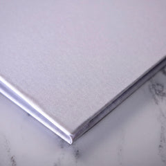 A close-up view of a white, textured surface, possibly a marble or stone, with a folded or closed object placed on top of it.