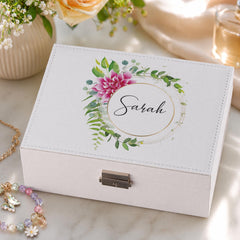A white jewelry box with a floral design and the name "Sarah" printed on it, placed on a marble surface.