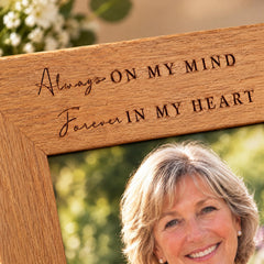 A woman with short blonde hair is smiling at the camera, with a wooden frame in the foreground.