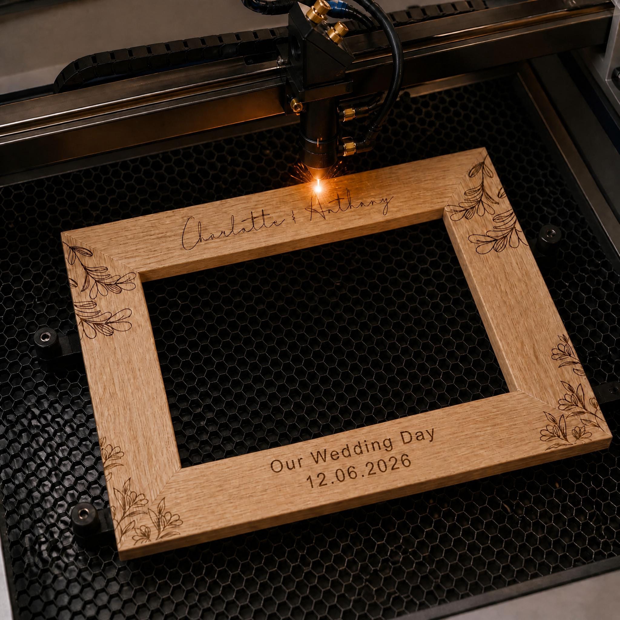 A wooden frame with a laser engraving of a floral design, placed on a metal frame and being processed by a laser engraver machine.