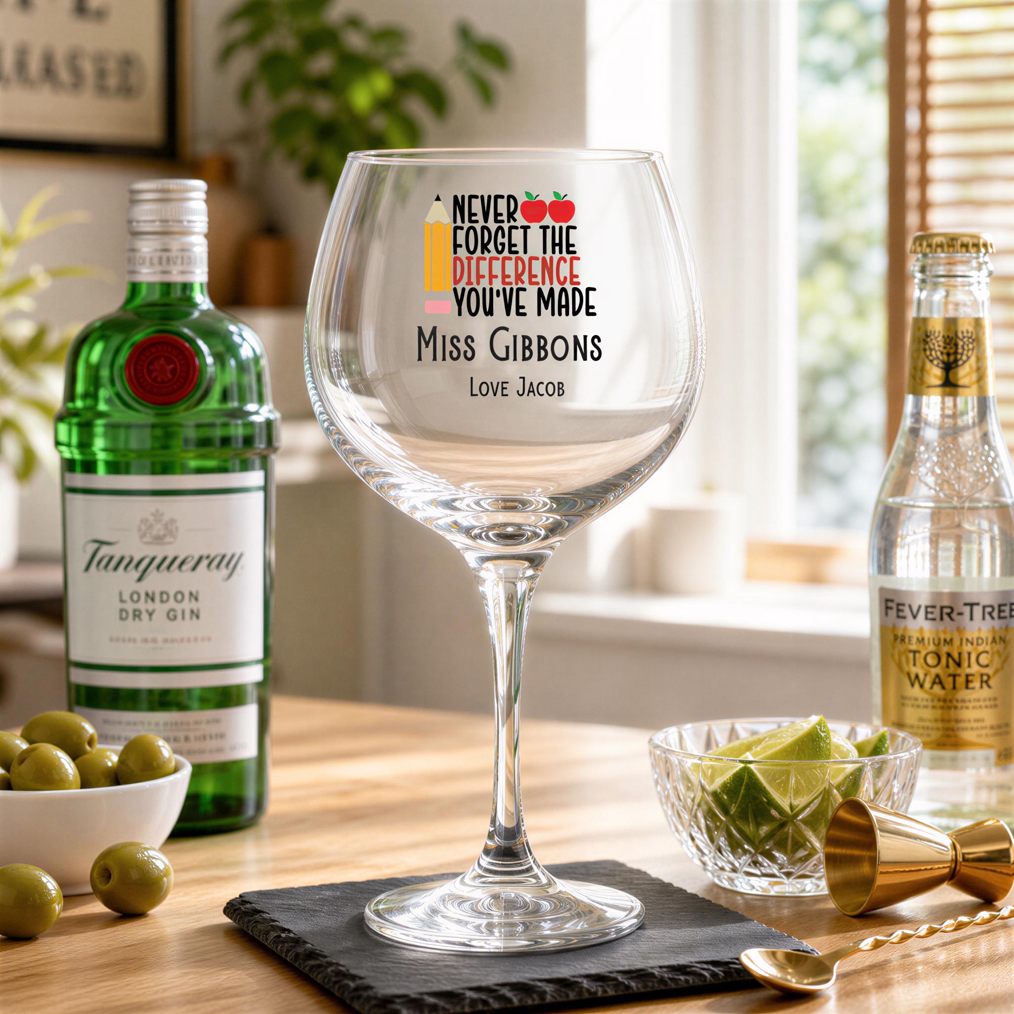 a table with a wine glass, a bottle of gin, and a bowl of olives. The wine glass has a message that says "Never forget the difference you've made Miss Gibbons Love Jacob".