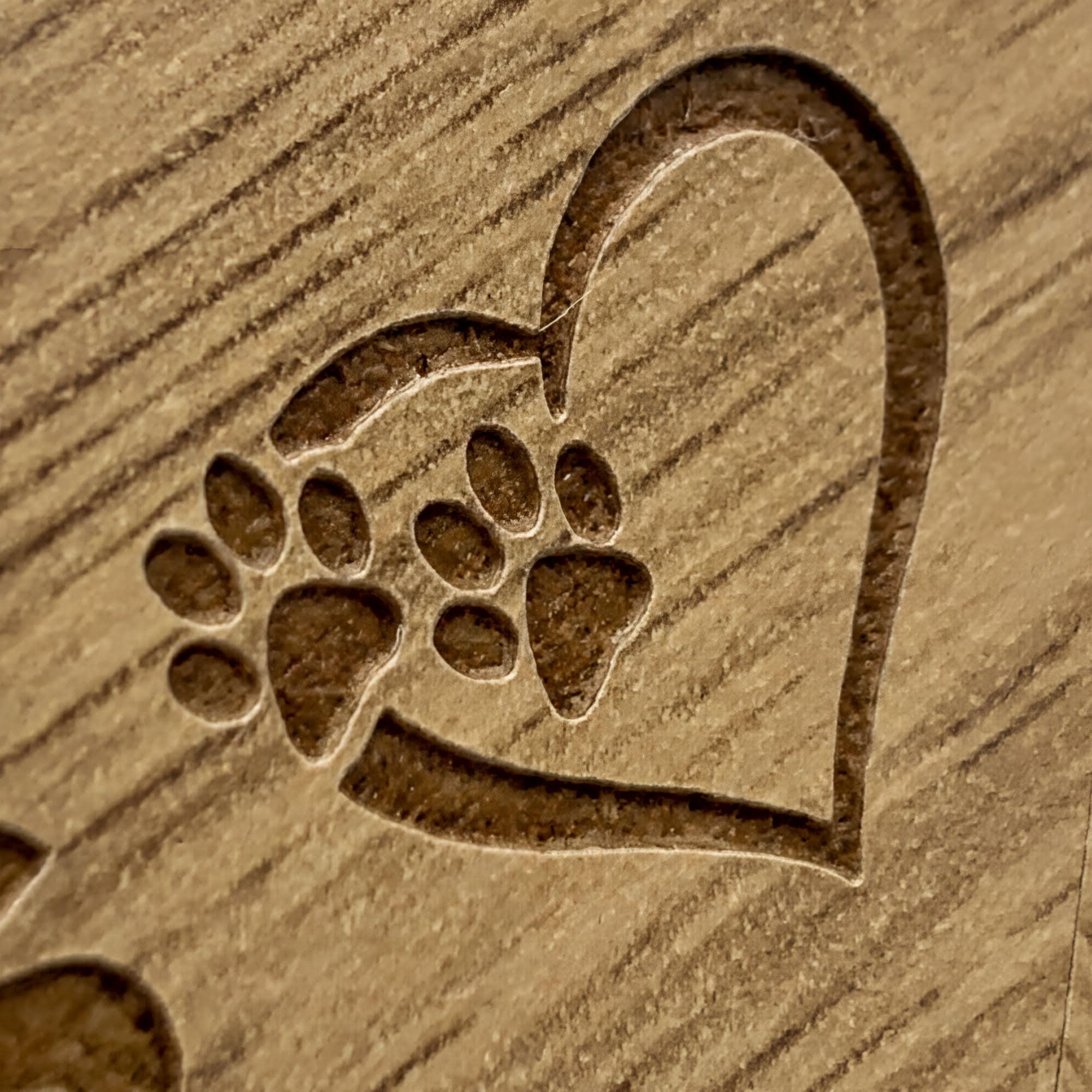 A heart-shaped design made of wood, featuring a pair of paw prints.
