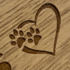 A heart-shaped design made of wood, featuring a pair of paw prints.
