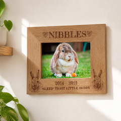 A wooden picture frame with a photo of a rabbit inside it, along with the text "NIBBLES" and "SLEEP TIGHT LITTLE BUDDY" engraved on it.