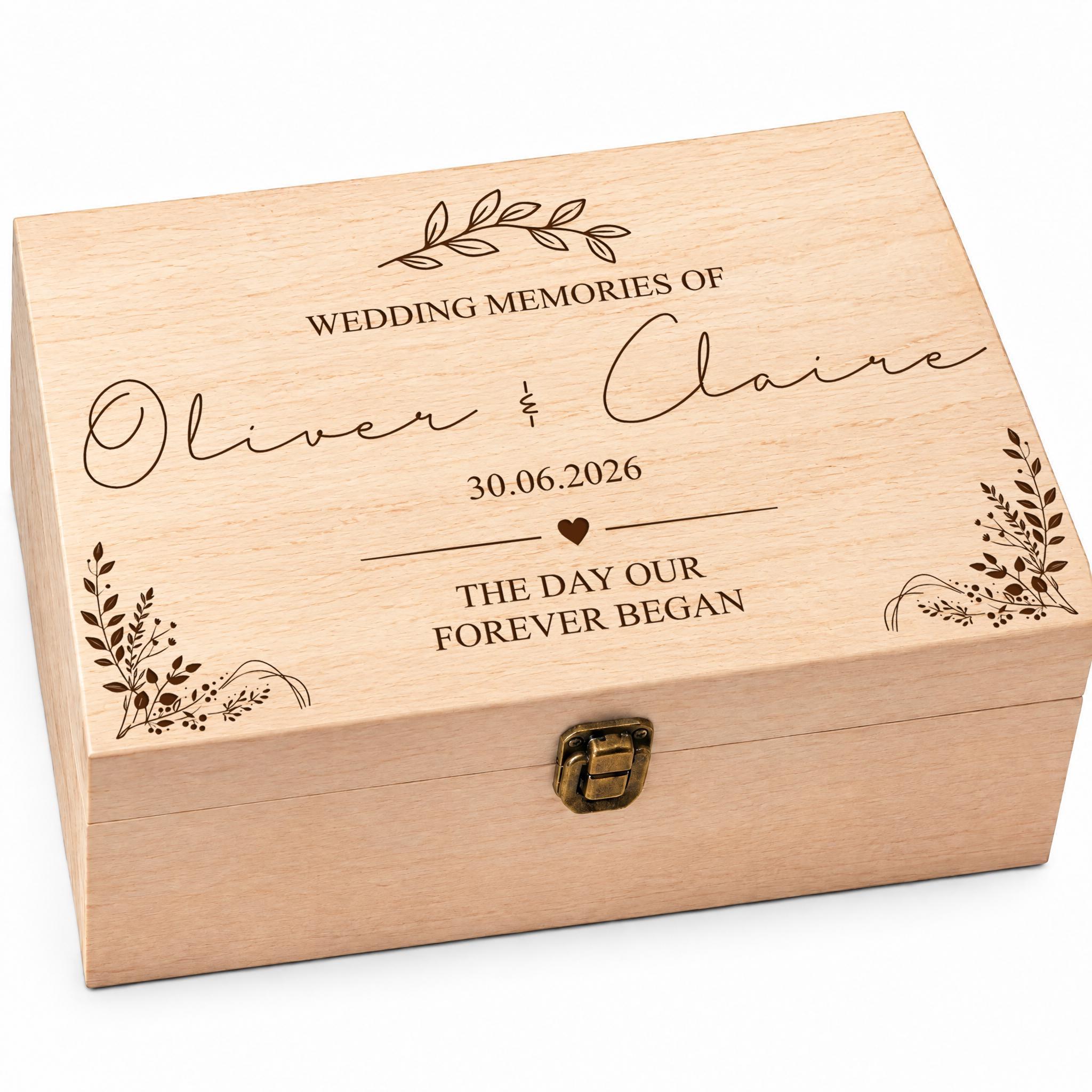 A wooden box with the text "Wedding Memories of Oliver & Claire" engraved on it, along with the date "30.06.2026" and the phrase "The day our forever began".