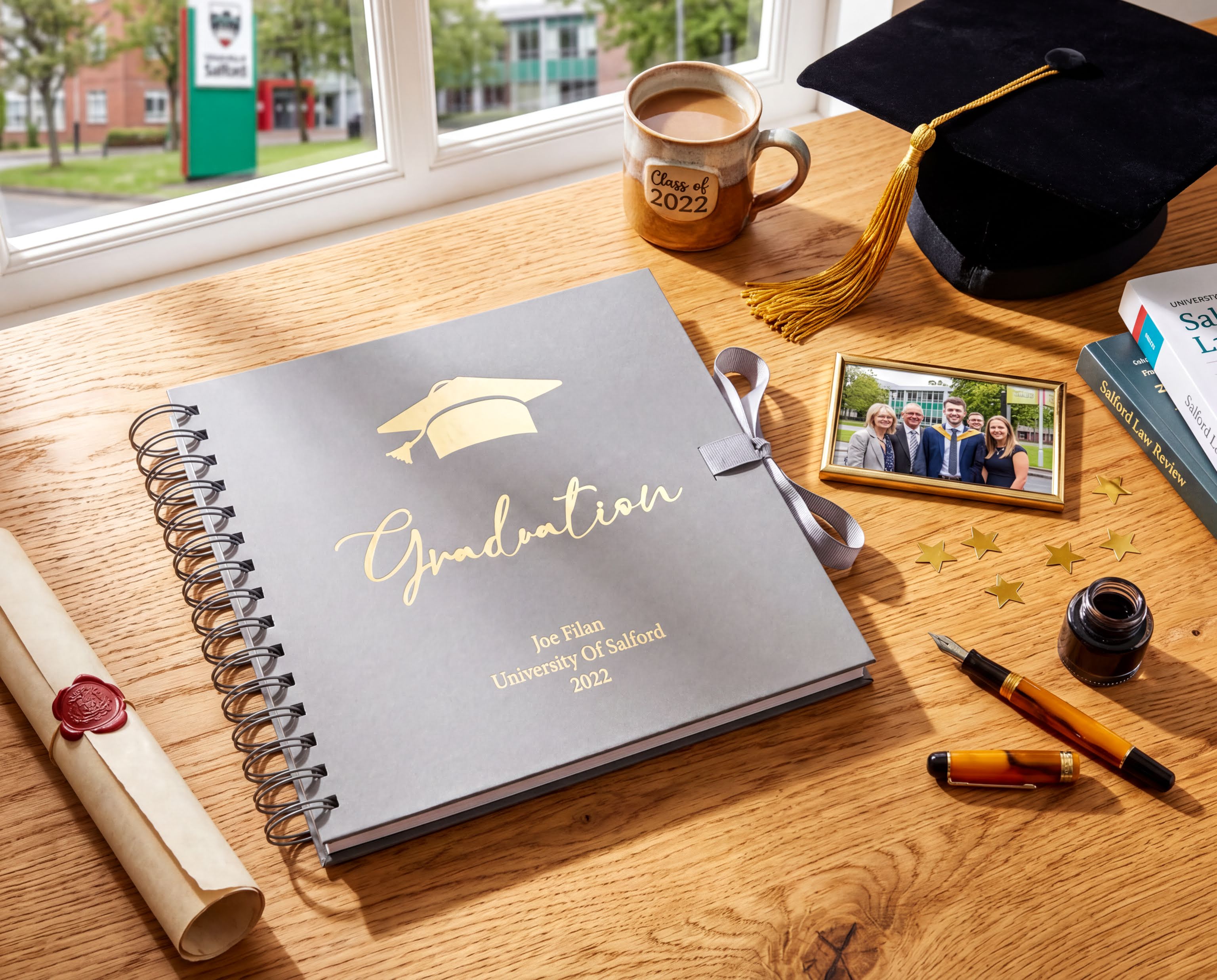 a graduation-themed desk with various items, including a graduation cap, a graduation album, a framed photo, a graduation gown, a graduation tassel, a graduation mug, a graduation book, a graduation pen, and a graduation gown.