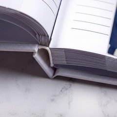 an open book with blank pages, resting on a white marble surface.