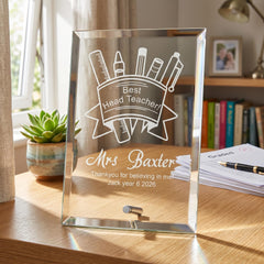 A glass frame with a personalized message on it, placed on a wooden desk in front of a window.