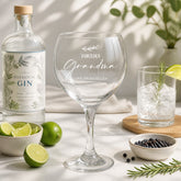 a table with a bottle of Botanical Gin, a wine glass with a personalized message, a glass of water, a bowl of black peppercorns, and some lime wedges.