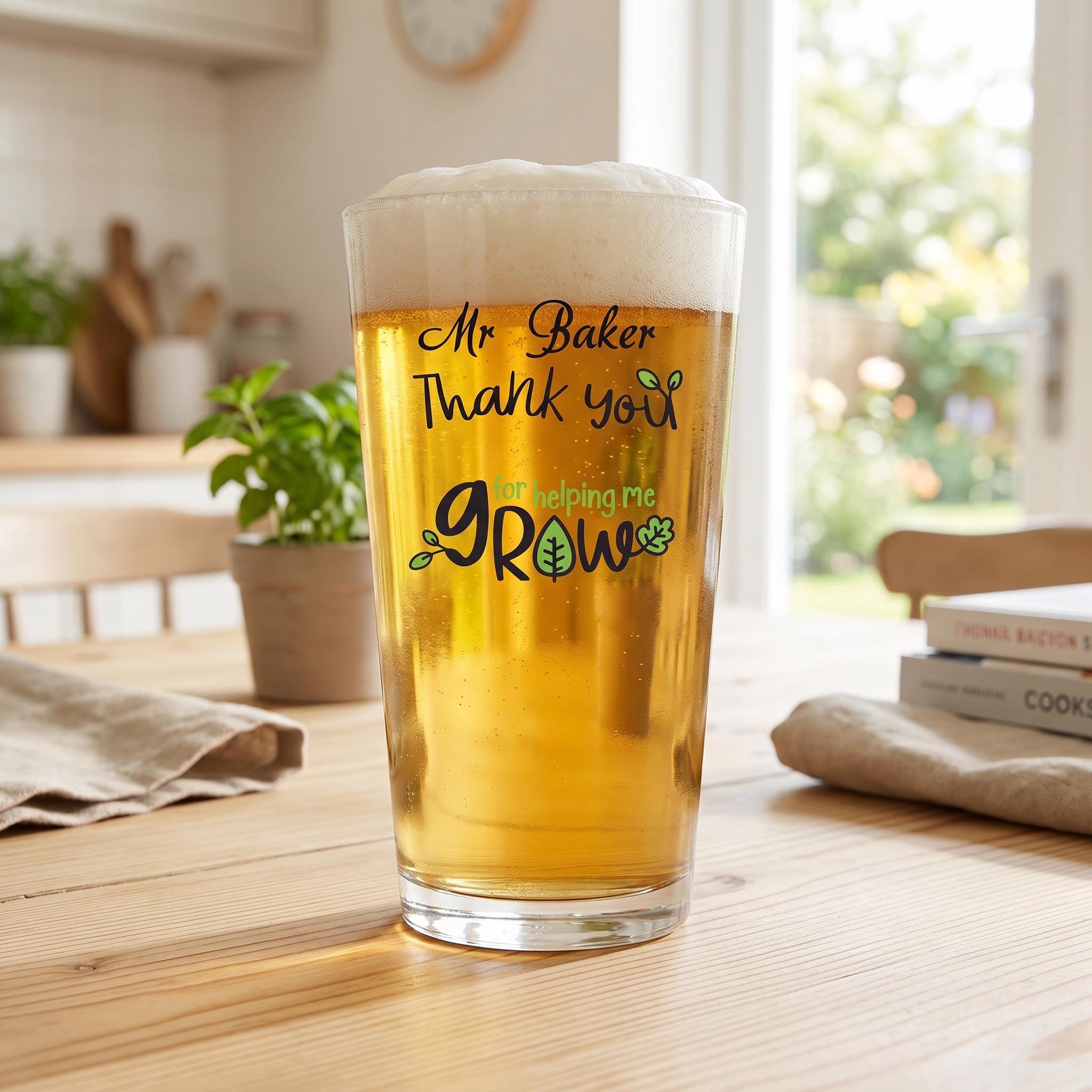 A tall glass of beer with a message on it, sitting on a wooden table in a kitchen.
