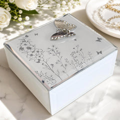 A decorative box with a floral design and a butterfly motif, placed on a marble surface.