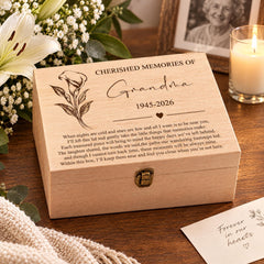 a wooden box with a heartfelt message engraved on it, placed on a wooden surface next to a candle and a card.