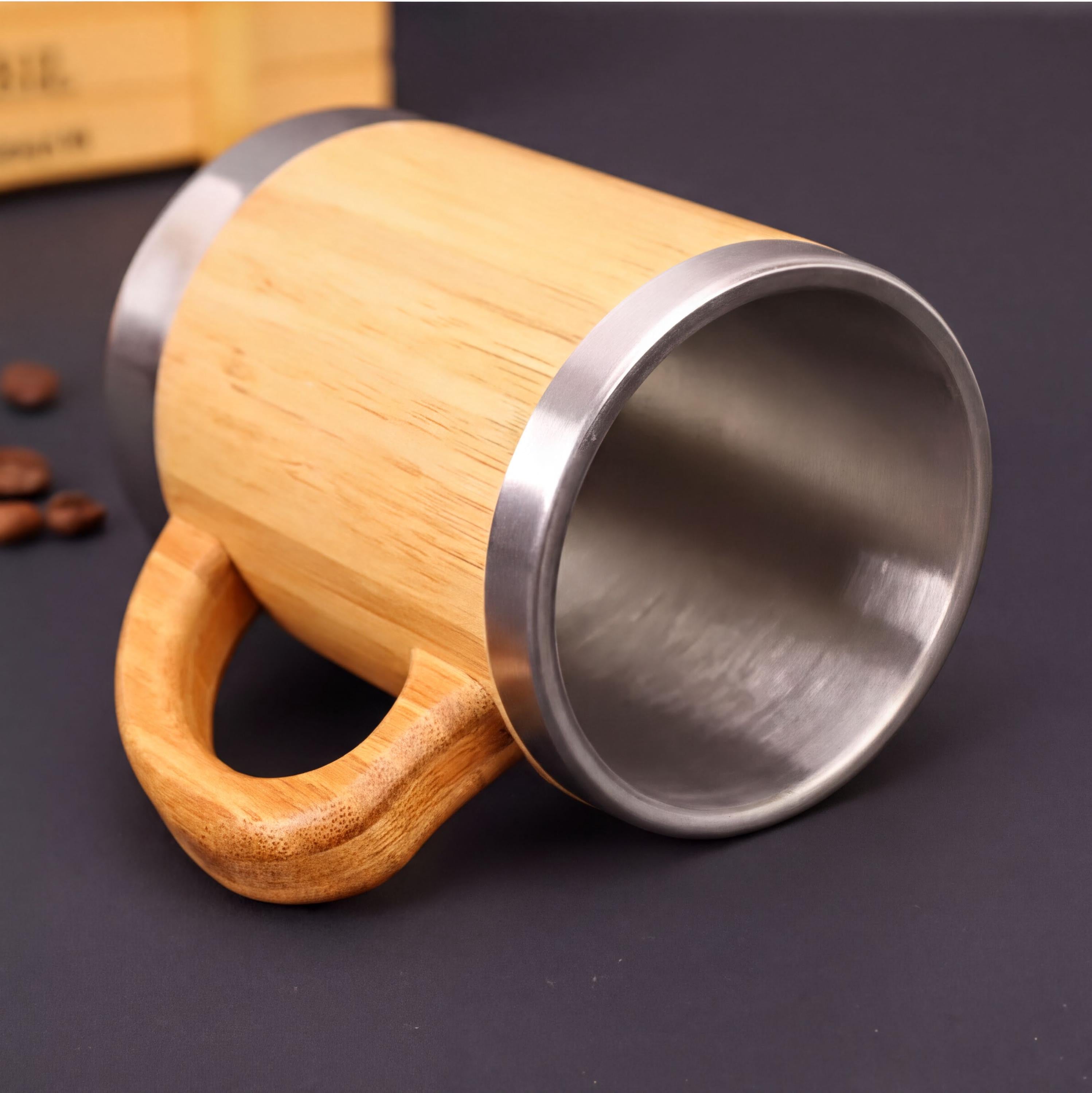A wooden mug with a silver interior sits on a dark surface, surrounded by coffee beans.