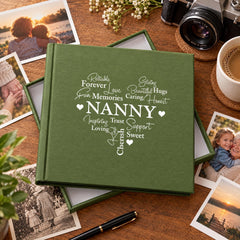A green photo album with the word "NANNY" printed on it, surrounded by various photographs and a camera on a wooden surface.