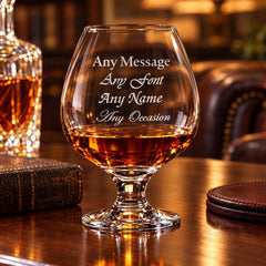 A personalized glass of whiskey with the inscription "Any Message Any Font Any Name Any Occasion" engraved on it, placed on a wooden table.