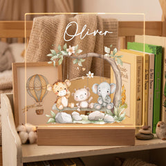 A wooden shelf displaying a framed illustration of three cartoon animals, including a giraffe, a lion, and an elephant, sitting on a swing. The name "Oliver" is written above the illustration.