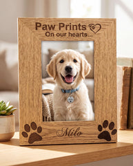 A wooden picture frame with a photo of a golden retriever dog inside, and the frame has paw prints and the name "Milo" engraved on it.