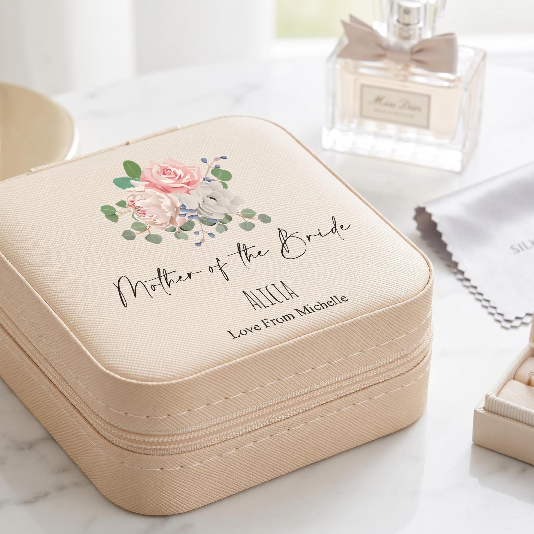 A beige cosmetic case with a floral design and text that says "Mother of the Bride" and "ALICEa Love From Michelle" printed on it.
