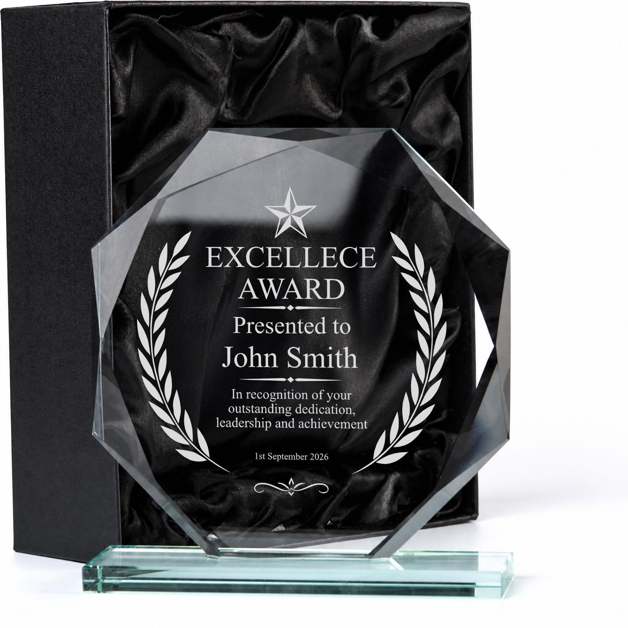 a clear glass award with a black background and white text, presented in a black box.