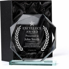 a clear glass award with a black background and white text, presented in a black box.