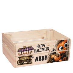 A wooden crate with a Halloween-themed design on it. The crate has a pumpkin and a trick or treat wagon illustration, along with a text that says "Happy Halloween" and "Abby" printed on it.