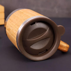 A wooden mug with a brown lid and a black handle, sitting on a dark surface.
