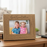 Wooden photo frame with 'Great-Grandchildren' engraving, displaying a photo of two children, on a table.