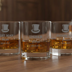 Three whiskey glasses with engraved names on a wooden surface