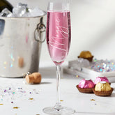 Pink champagne flute with 'Majestic' text on a festive background with chocolates and confetti.