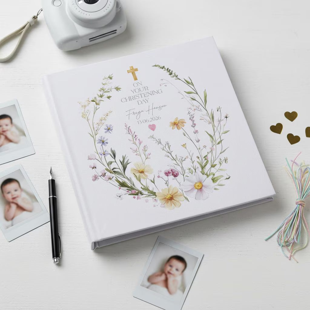 Personalized photo album with floral design on a white surface with photos and a camera.