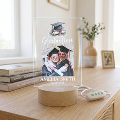 a graduation celebration with a photo of two women in caps and gowns, surrounded by graduation-related items such as a graduation cap, mortarboard, and a vase with greenery.