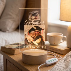 a graduation-themed lighted display with a photo of two women wearing graduation caps and gowns, along with the name "Amelia Smith" and the date "16-09-2026".